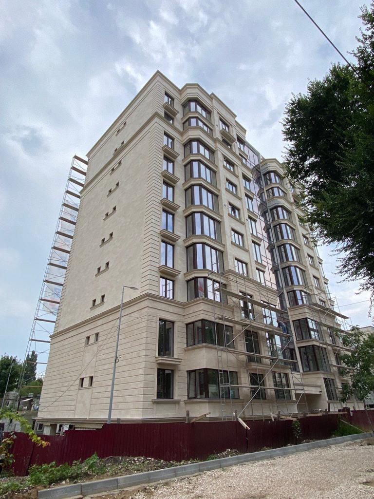 Turnul blocului cu bovindouri suprapuse și bosaje orizontale din plăci flexibile bej, gard în față